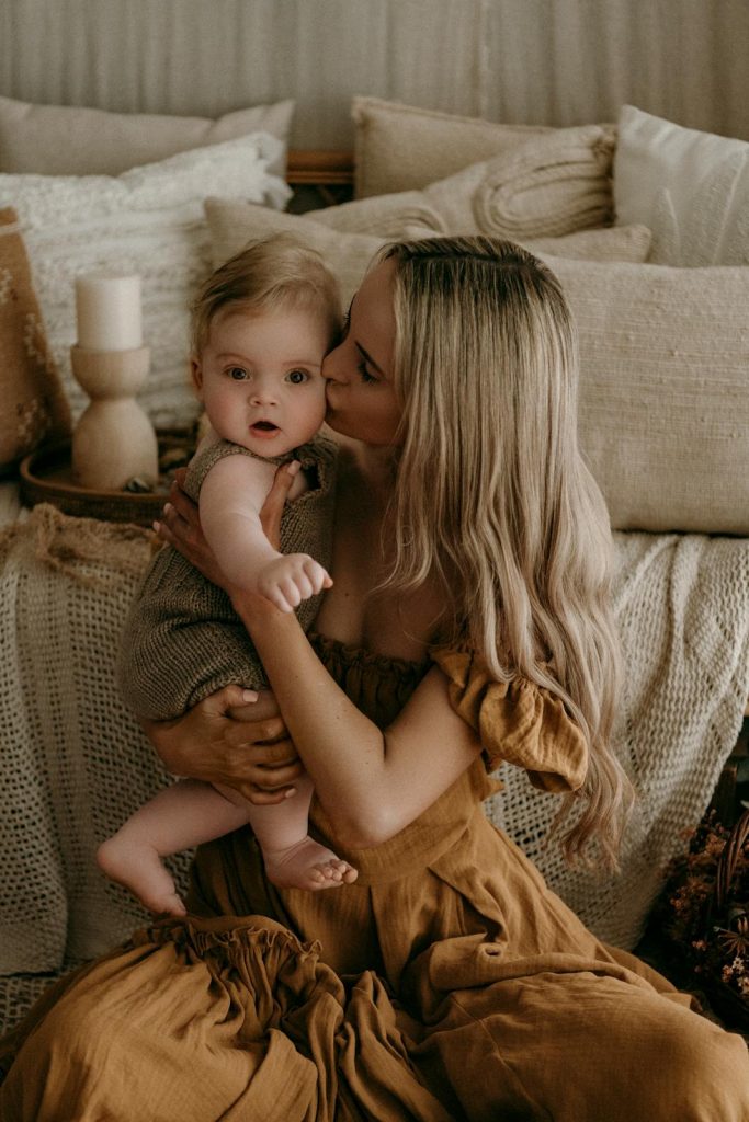 A mother lovingly holds her baby, creating a cozy and warm family portrait.