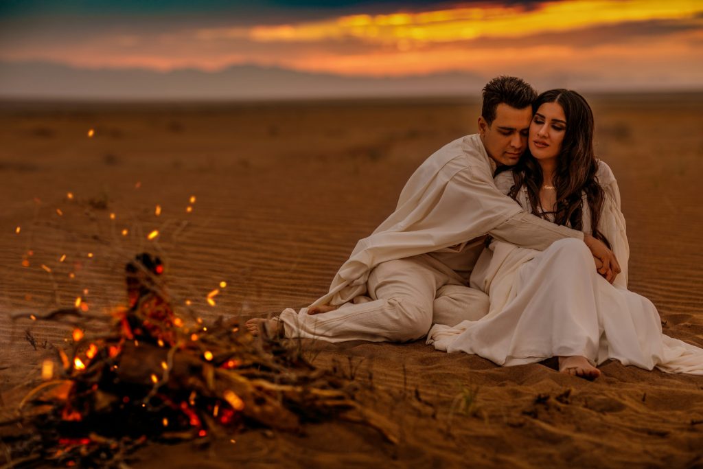 A man and a woman sitting next to a campfire